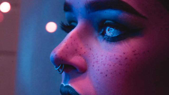 face the color of dark pin and blue with dark freckles with a double nose piercing. Eyes are glowing which gives the image a technology look and feel