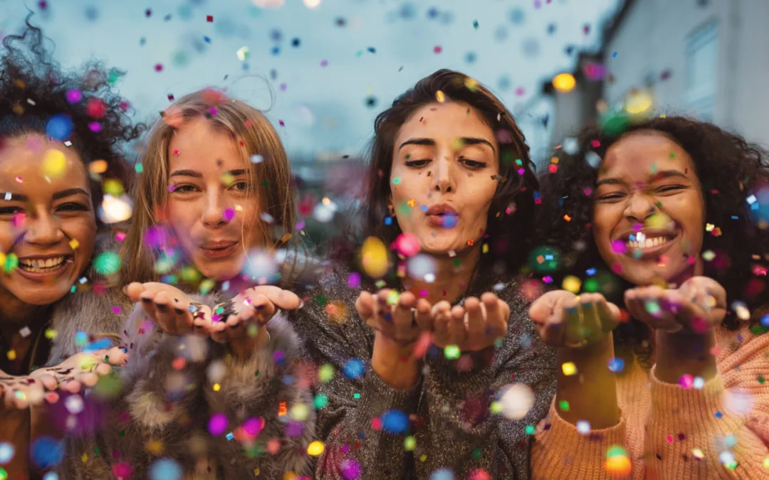 Women celebrating blowing confetti